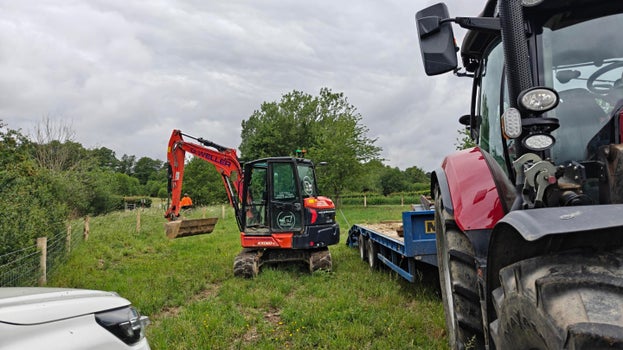 Image of a large tractor and trailer with an excavator just offloaded to start work on the new bridge